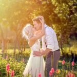 Bride holding groom’s head with both hands at a Miami wedding venue, hazy sunset backdrop, warm tones, romantic moment by Alito Photography.