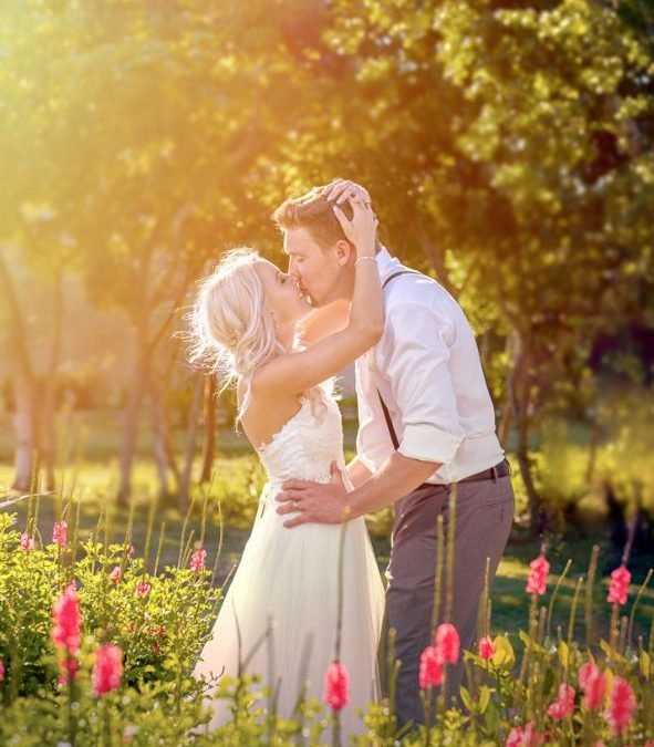 Bride holding groom’s head with both hands at a Miami wedding venue, hazy sunset backdrop, warm tones, romantic moment by Alito Photography.