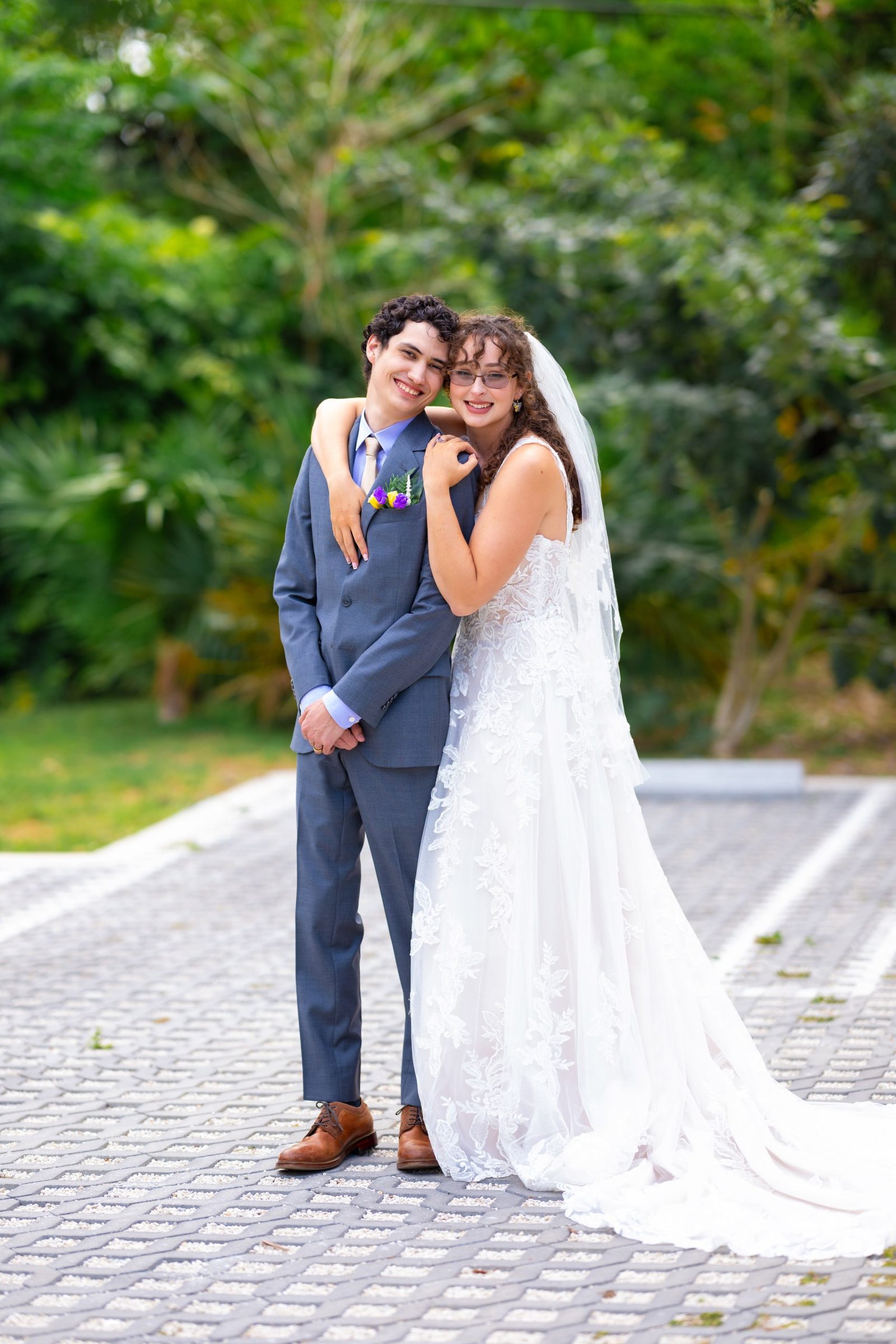 Bride in a flowing white dress embraces her groom in a gray suit during their wedding day in Coconut Grove, Miami wedding photo by Alito Photography.