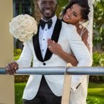 Smiling bride hugs groom from behind holding her bouquet at their Hard Rock Dominican Republic destination wedding