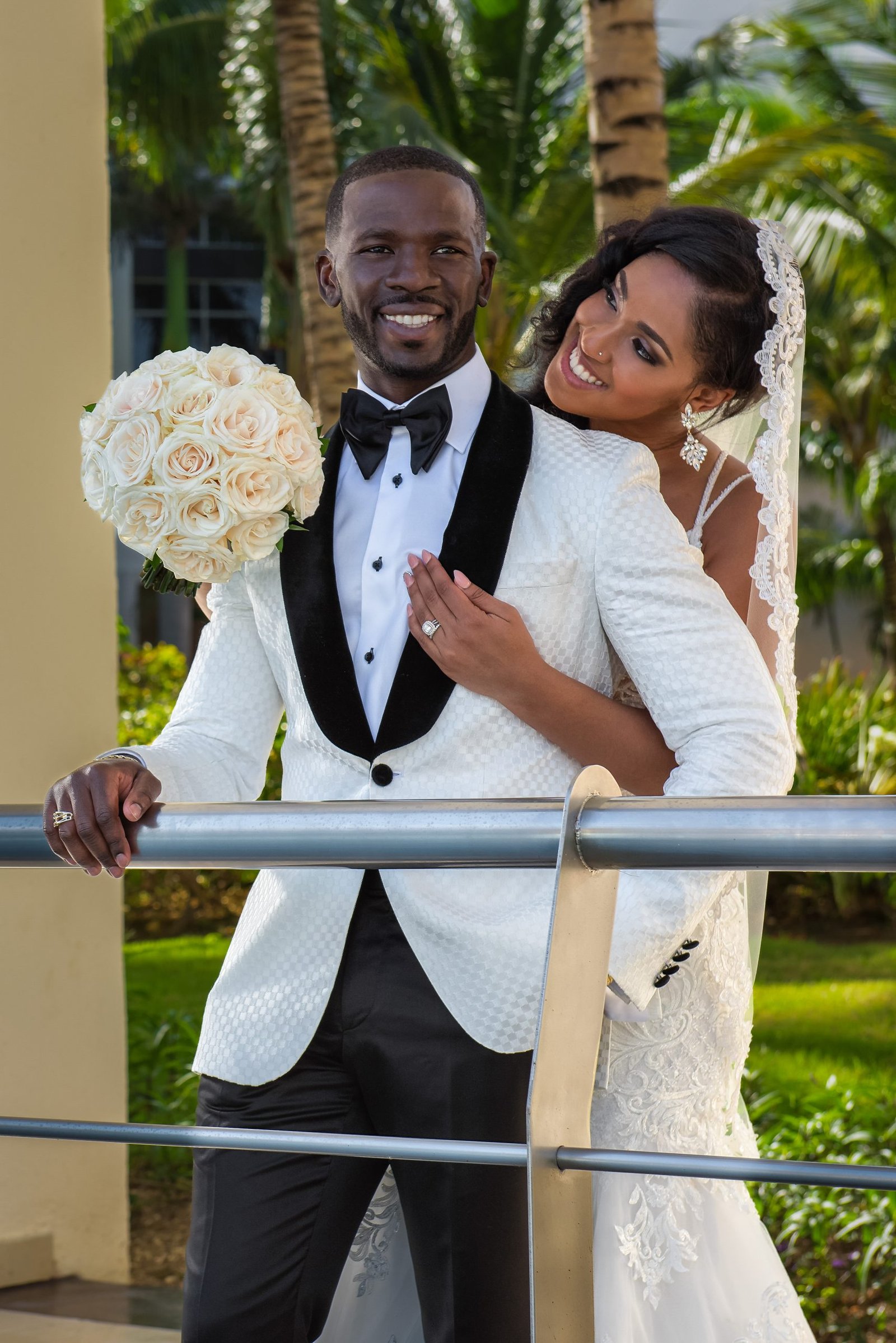 Smiling bride hugs groom from behind holding her bouquet at their Hard Rock Dominican Republic destination wedding
