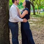 Engaged couple standing under a tree in a park, gazing into each other’s eyes