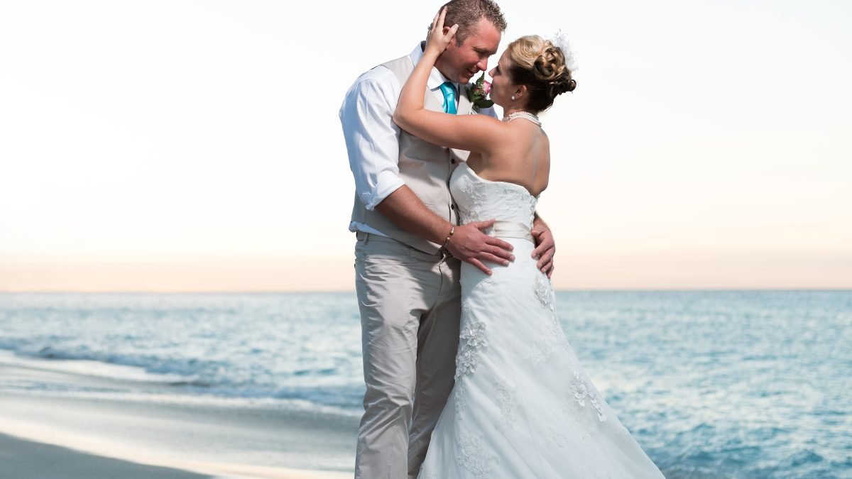 Miami wedding couple embracing on the beach at sunset after their ceremony, captured in a natural, candid moment.