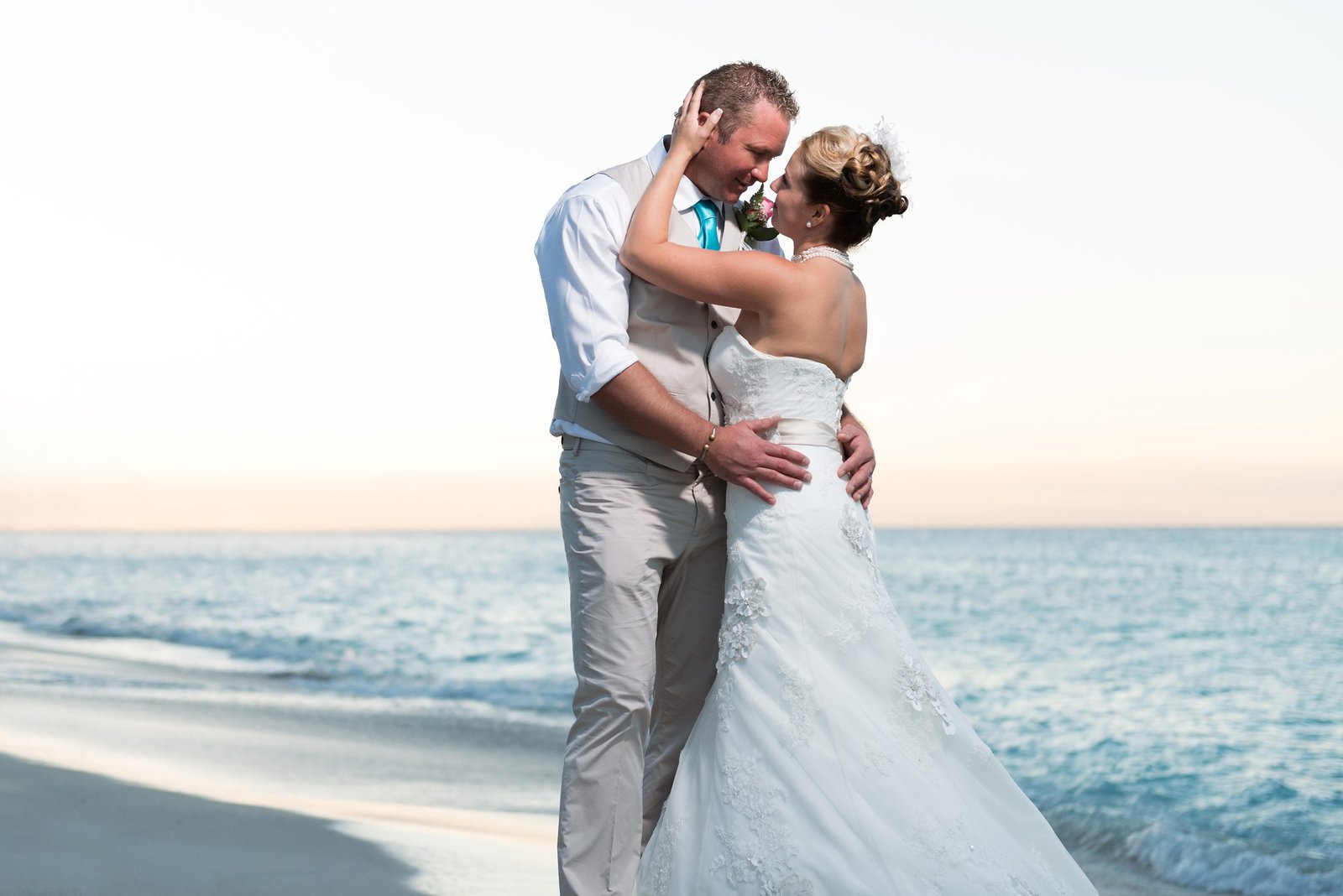 Miami wedding couple embracing on the beach at sunset after their ceremony, captured in a natural, candid moment.