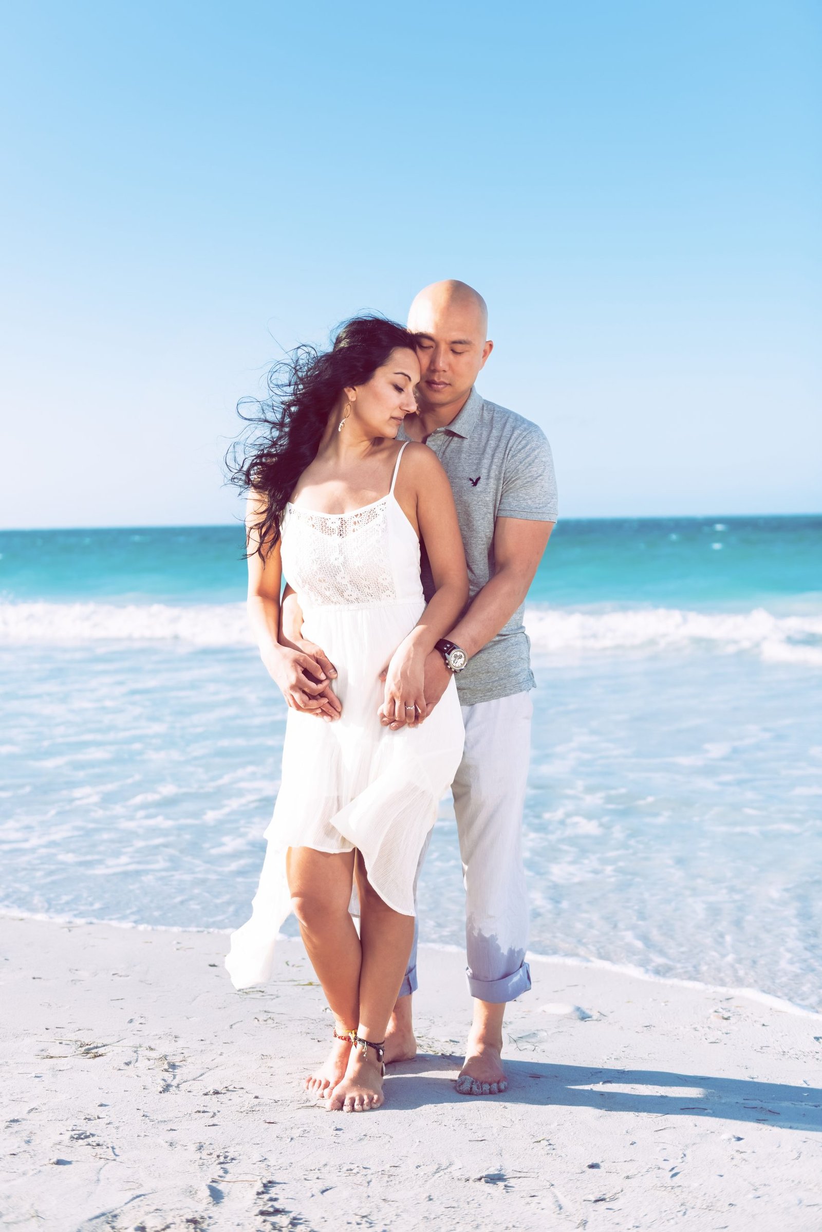 A newly engaged couple posing naturally on a Miami beach during sunset, captured by Alito Photography.