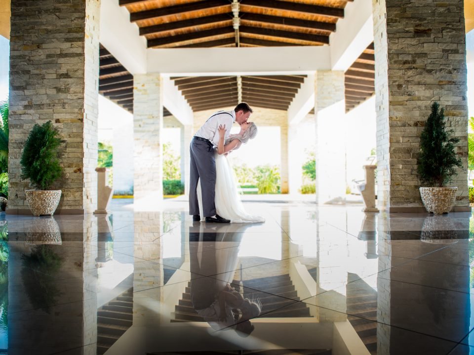 Groom dipping the bride for a romantic wedding kiss with a beautiful hotel view, photographed by Alito Photography.