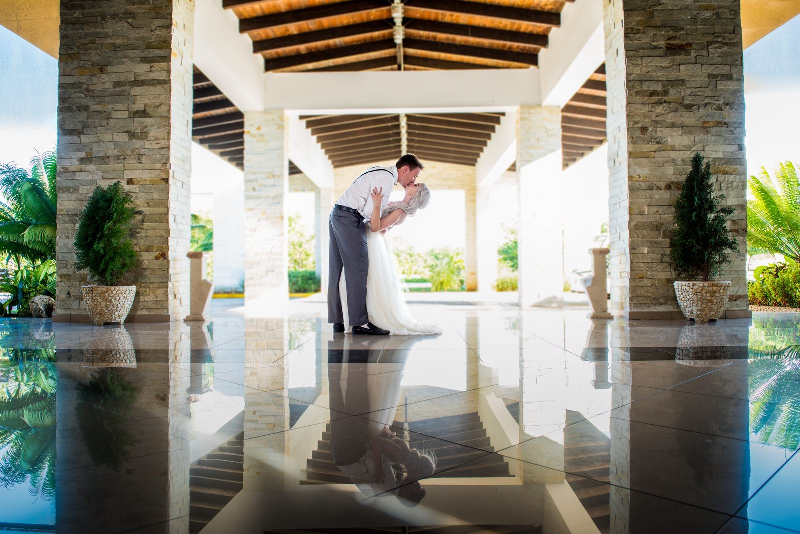 Groom dipping the bride for a romantic wedding kiss with a beautiful hotel view, photographed by Alito Photography.
