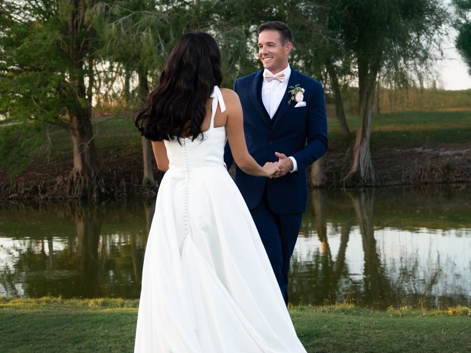 Newly married couple smiling and holding hands at The Club at Ibis in West Palm Beach, captured by Alito Photography, South Florida wedding photographer.