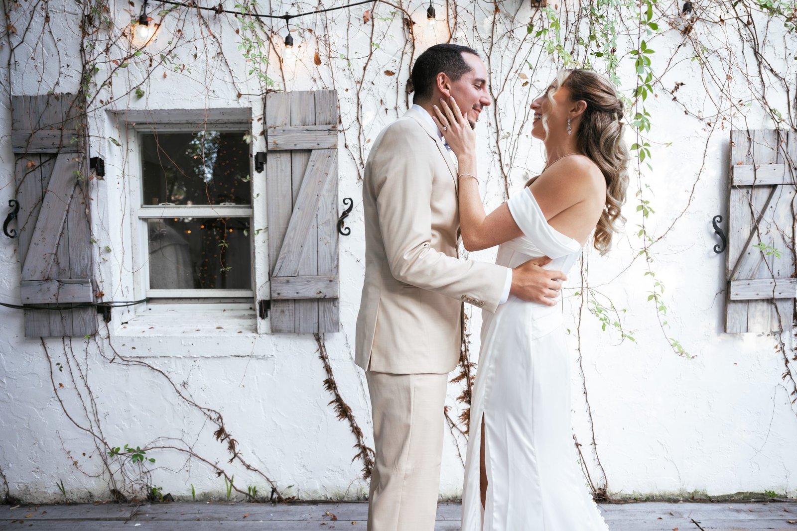 Wedding couple sharing an emotional first look in their wedding attire, hugging and kissing with joy